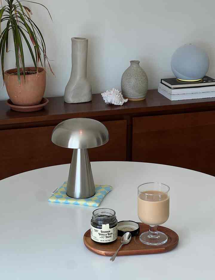 Natural-toned living room featuring wooden cabinet and minimalist white dining table with modern lamp, creating a calm atmosphere