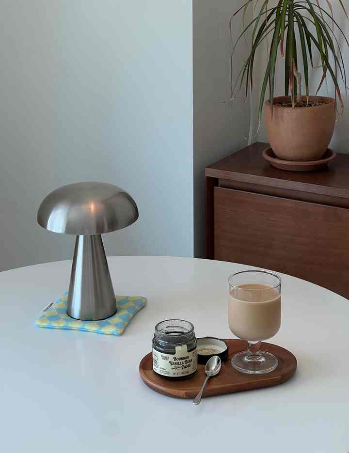 Natural color and wood-toned multipurpose dining table featuring a simple table lamp and a cozy home cafe setup
