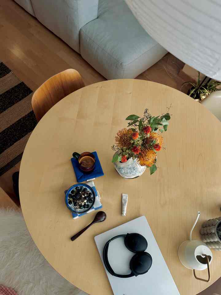 Natural wood-toned studio living and dining area featuring white sofa and round table with home cafe vibe
