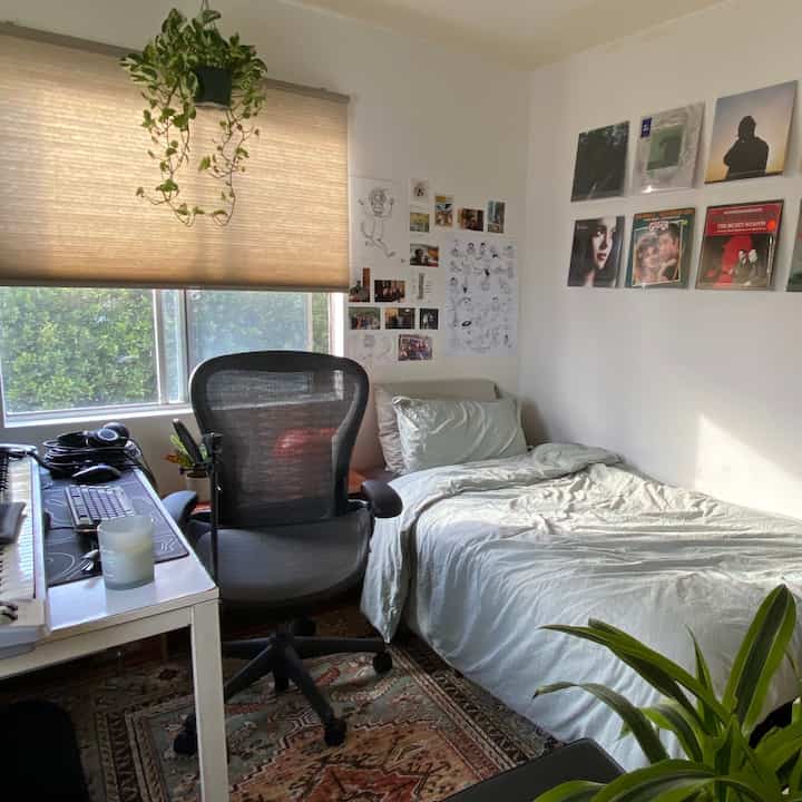 Natural-toned single household home office space featuring a Herman Miller chair, single bed, and beige blinds creating a cozy atmosphere