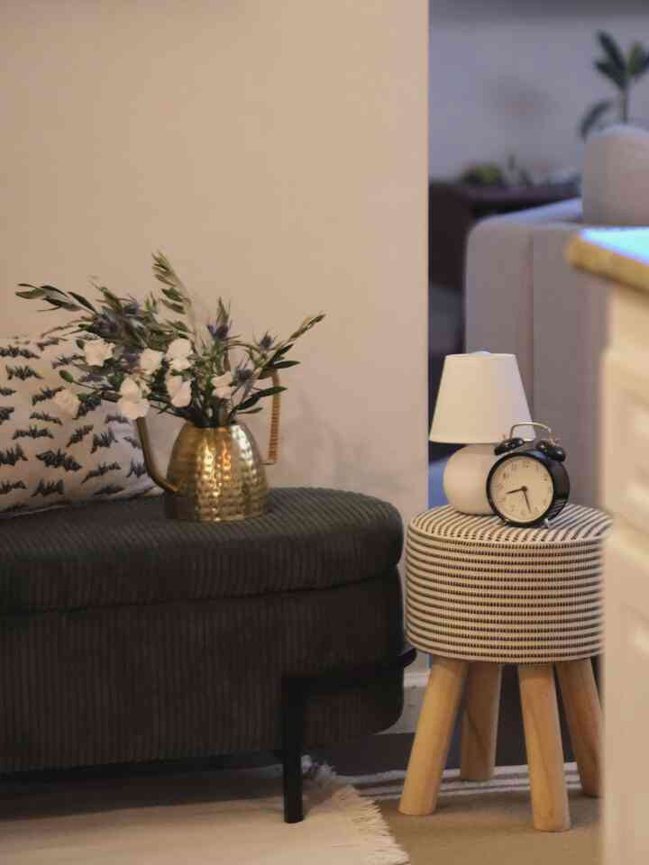 Natural color entrance space featuring a green ottoman and brass vase with flowers, creating a cozy atmosphere
