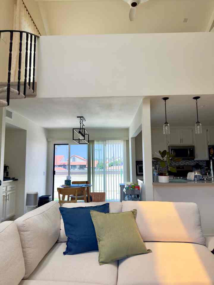 White and natural-tone living room and kitchen featuring modular sofa and cushions creating a cozy atmosphere