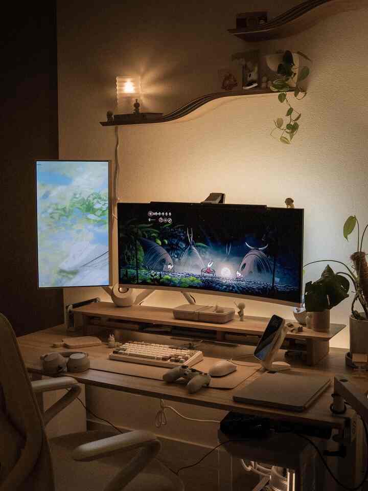 Cozy Japandi-style home office with warm wood tones and white elements, featuring dual monitors and gaming devices