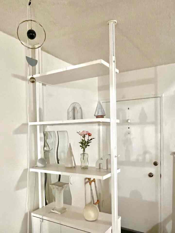 White-toned entrance space featuring a simple shelf with small decor items, creating a calm and clean atmosphere