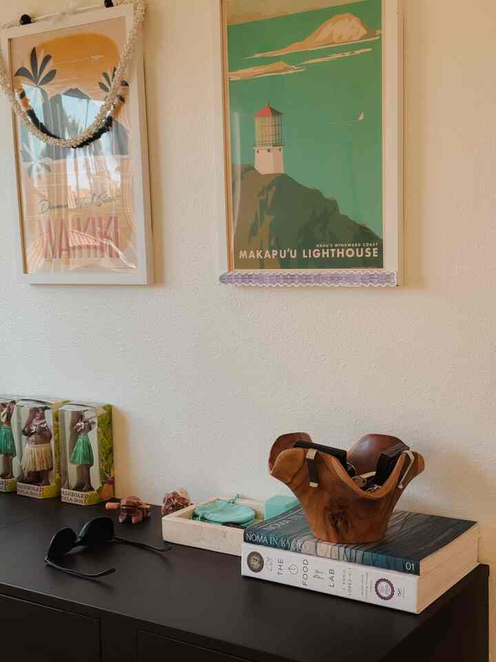 Entrance with white walls and black storage cabinet, featuring Hawaiian-themed posters and natural wood accessories