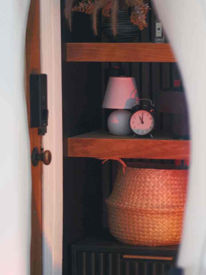 White and brown toned entrance featuring shelves with a table lamp, clock, and woven basket creating a cozy cafe style