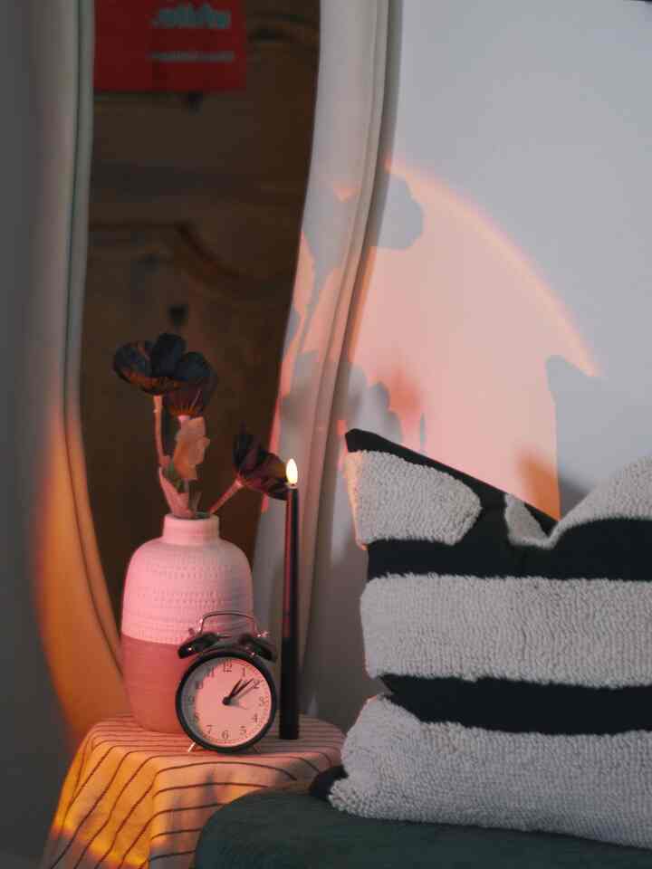 Cozy entrance setup featuring warm orange lighting, black-and-white cushion on bench, and a small table with candle and clock
