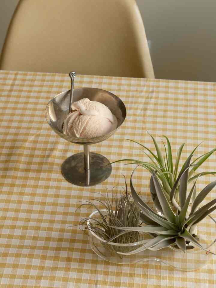 Yellow gingham tablecloth with a silver metal cup on a dining table creating a warm and cozy atmosphere