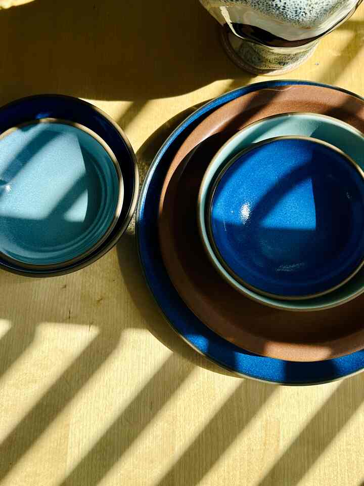 Blue and brown plates arranged on a wooden dining table under natural light