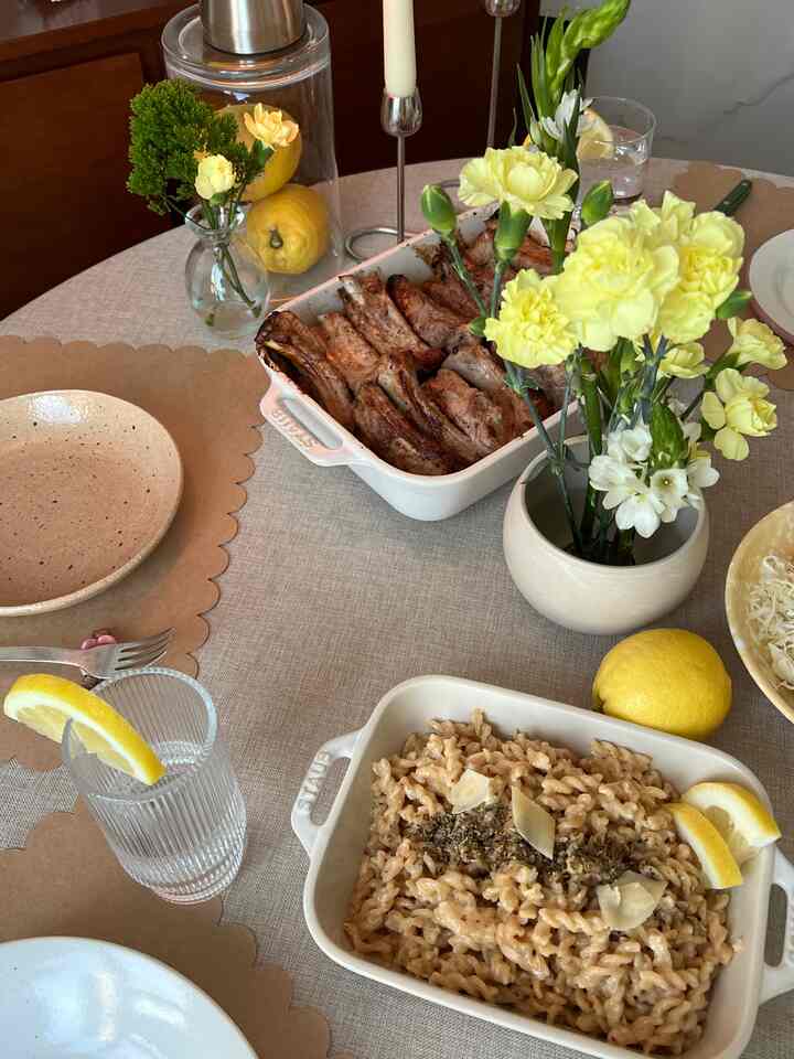 Beige-toned apartment dining table featuring brown paper placemats, yellow floral vases, and stoneware dishes in a warm atmosphere