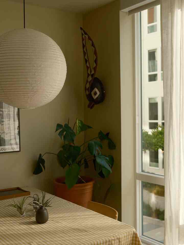 Beige-toned dining room featuring a gingham tablecloth and a central paper pendant light adding warmth in a natural setting