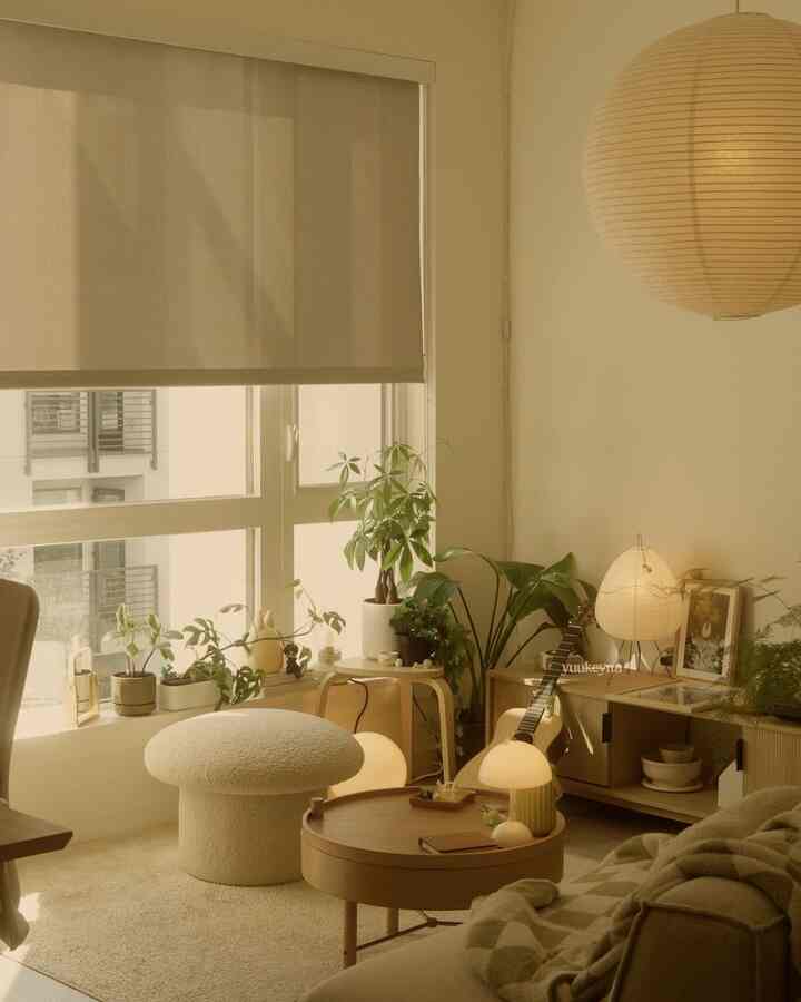 Warm natural tone living room featuring cozy sofa, round coffee table, and numerous plants creating a peaceful atmosphere