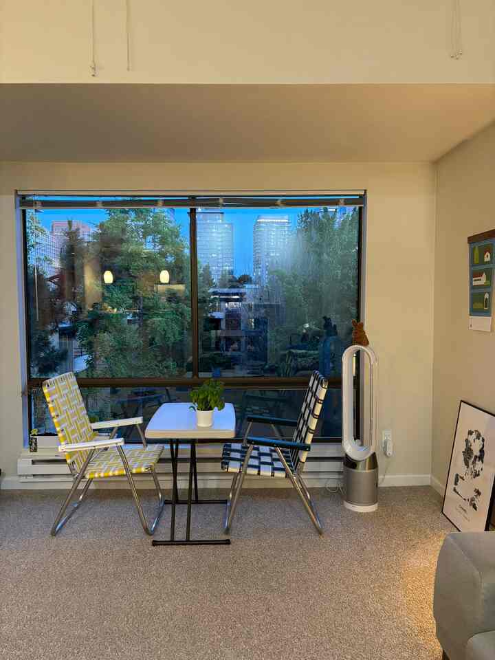 Balcony-style living room featuring two yellow and black patterned outdoor chairs and a white table with a calm evening atmosphere