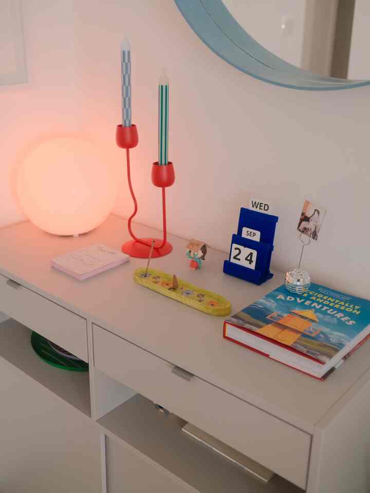 A white-toned entrance corner featuring a sideboard decorated with candles and objets, creating a minimal and cozy atmosphere