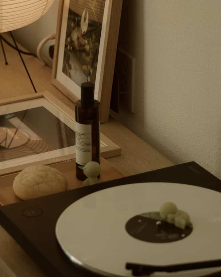 A cozy living room with warm wood tones and white accents, featuring a turntable and decorative objects creating a relaxed ambiance