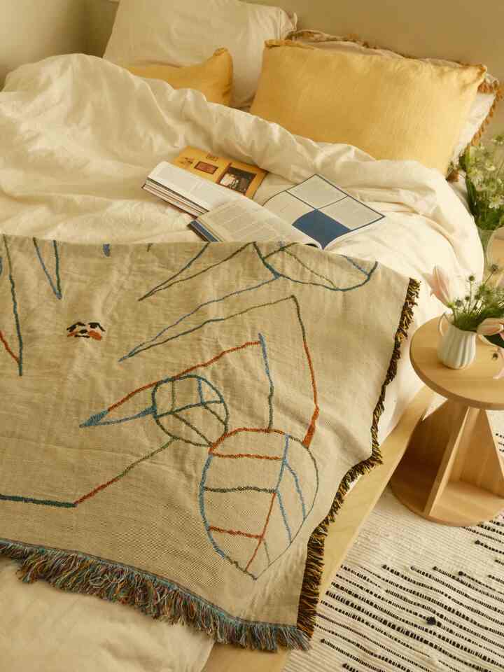Warm beige and yellow toned bedroom featuring wooden side table and blanket, creating a natural cozy atmosphere