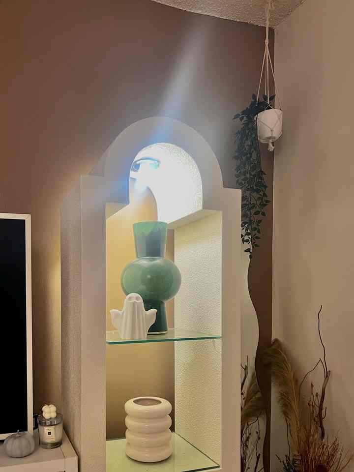 Beige-toned corner space featuring natural decor elements, wall sconce lighting, and hanging plant creating a cozy atmosphere