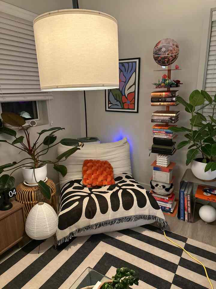 Light gray walled living room corner featuring a natural, simple lounge chair and plants with a cozy atmosphere