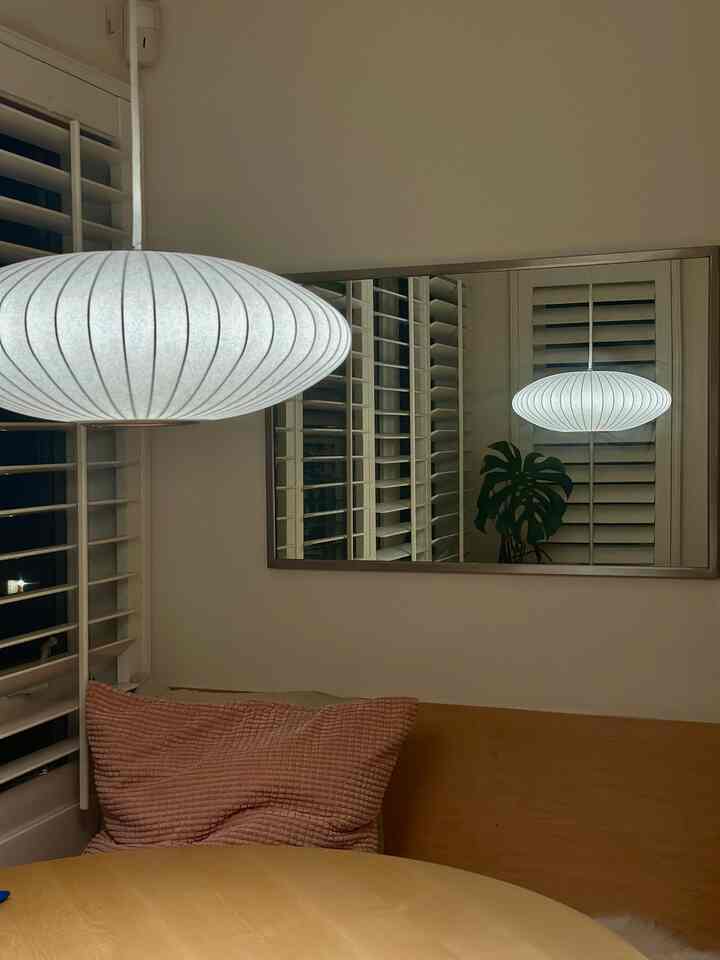Cozy dining room with white and wood tones, featuring a Nelson pendant light casting warm illumination