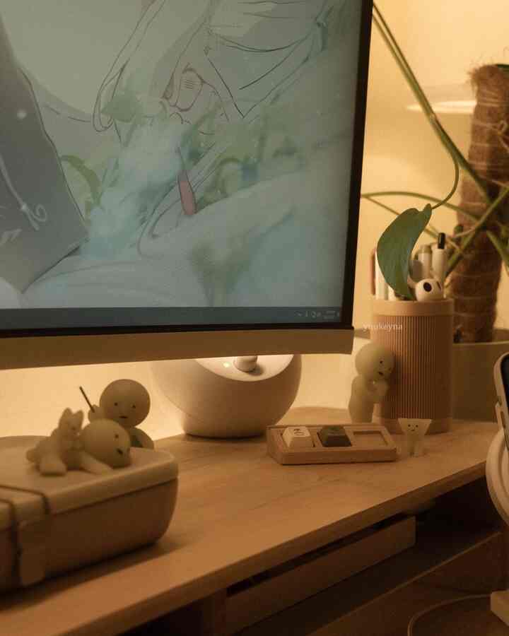 Natural-toned home office desk space with beige and wood tones, featuring plants and small figurines creating a cozy atmosphere