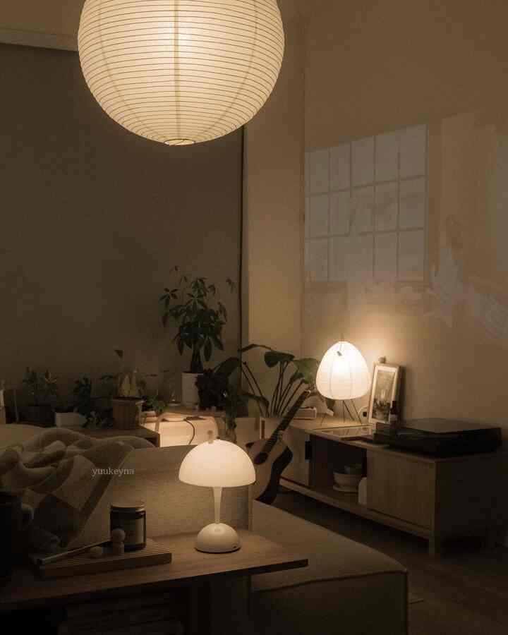 Natural color tone living room featuring a beige sofa, table lamps, and plants, with a natural modern atmosphere