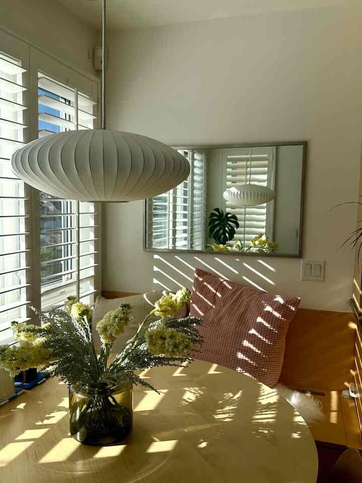 Warm beige-toned dining room featuring a wooden table with a vase of flowers and a pink cushion creating a cozy atmosphere