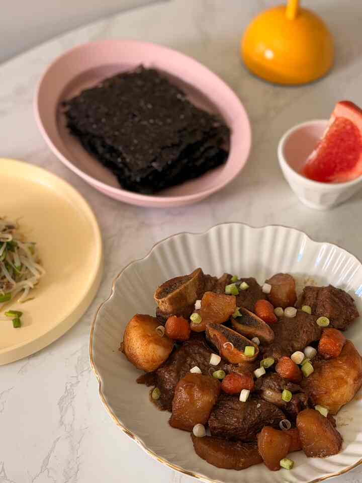 Natural kitchen space with Korean braised short ribs and side dishes on a white marble dining table