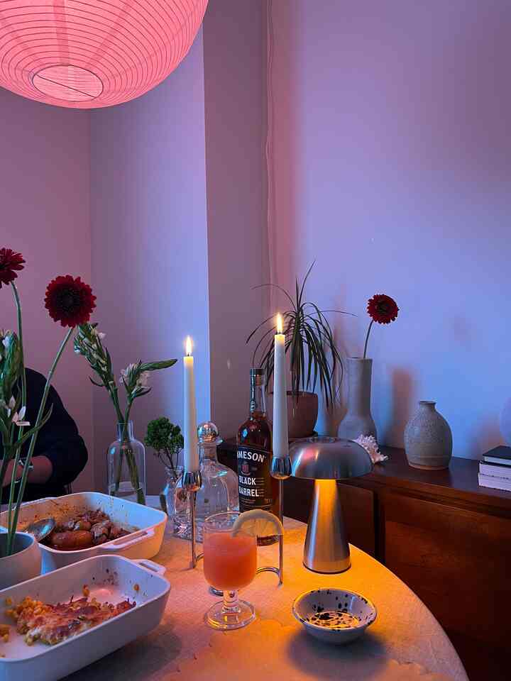 Warm orange-toned cozy dining room featuring a round table with candles, vases, and wooden furniture