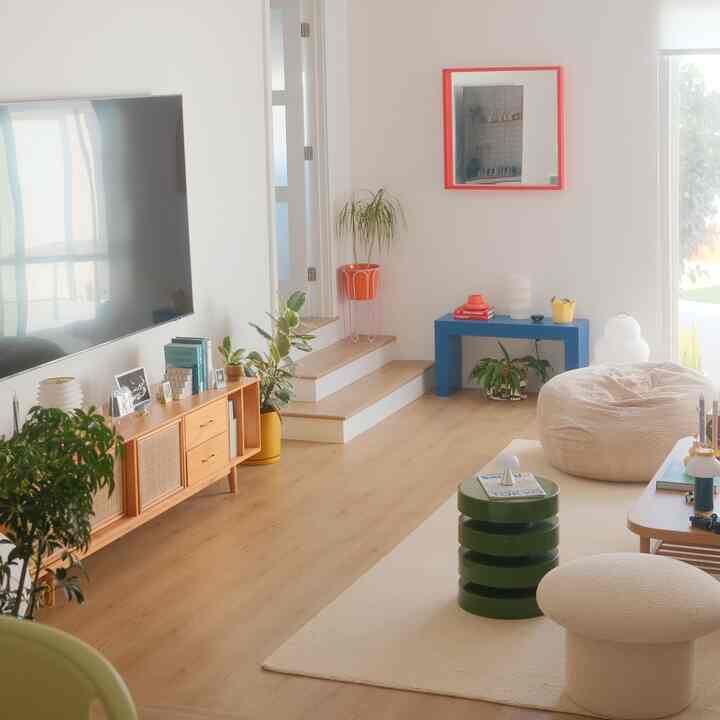 Bright living room featuring natural wood tones and white walls with a beige bean bag and green side table as distinctive accents