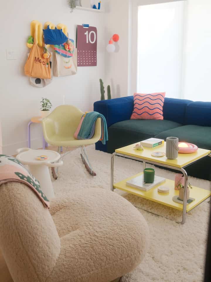 Bright living room with white carpet and yellow coffee table, featuring cozy armchairs and sofa creating a warm atmosphere