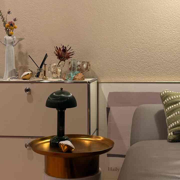 Beige-toned living room featuring a sideboard with art decorations and a gold side table topped with a table lamp, creating a cozy ambiance