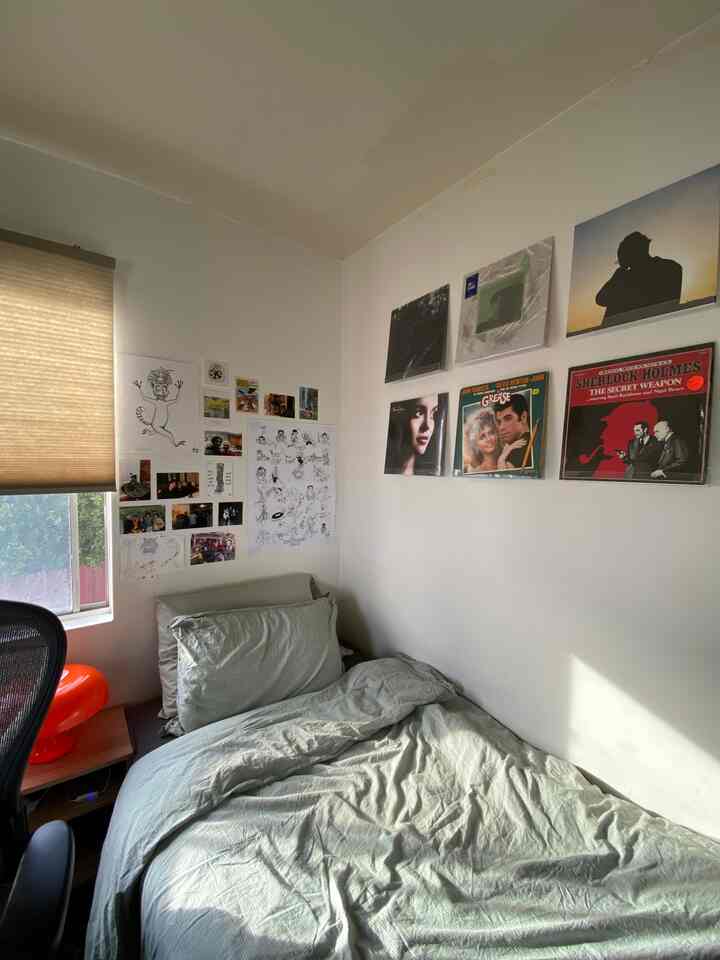 Bright beige and brown toned bedroom and home office featuring an orange mushroom lamp and vinyl record wall display, creating a cozy atmosphere