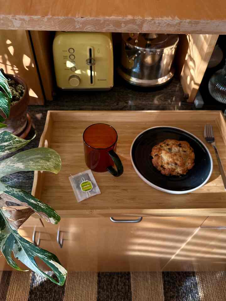 Warm brown and yellow toned kitchen featuring bamboo tray with mug and cookie, creating a cozy home cafe atmosphere