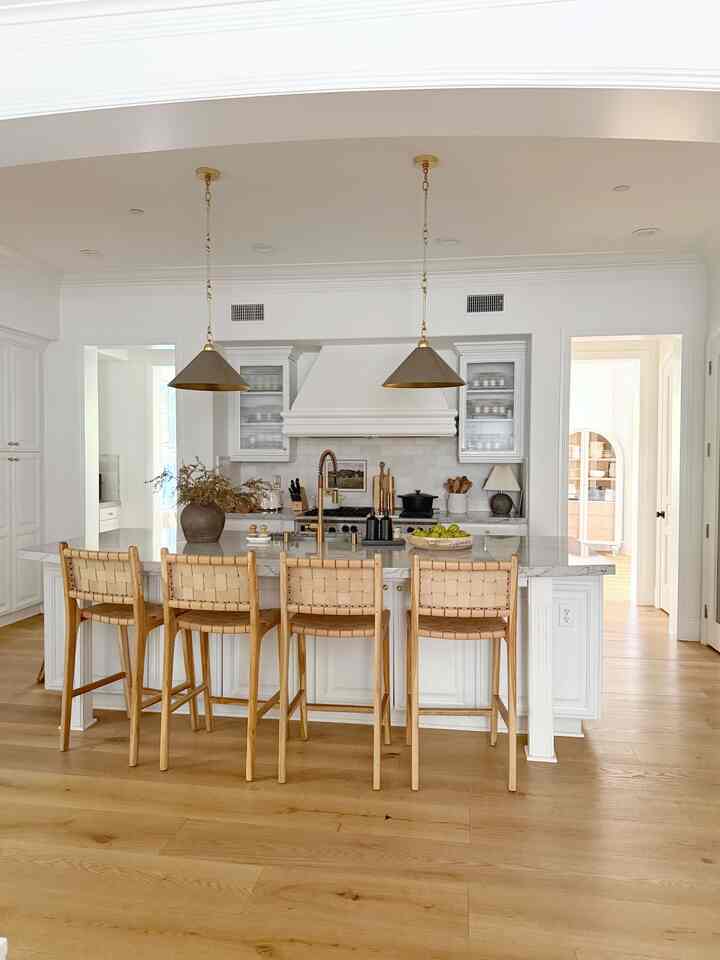 Natural color and white toned kitchen featuring wooden stools and pendant lights with a clean atmosphere