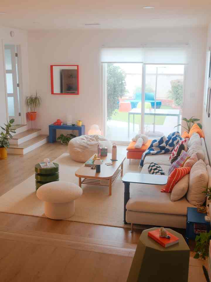 Natural color tones with orange accents in living room featuring large windows, sectional sofa, stools creating cozy atmosphere