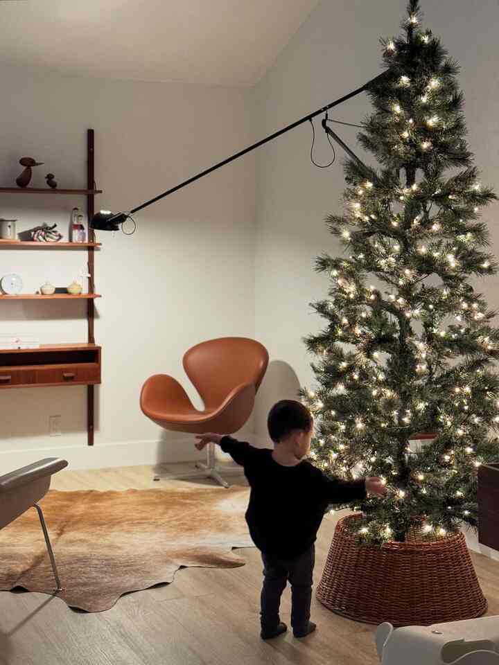 Warm wood-toned simple living room featuring a lit Christmas tree, a child, and a brown lounge armchair creating a cozy atmosphere