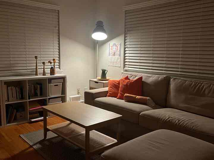 A white and beige toned living room featuring a sectional sofa, coffee table, and floor lamp with a modern, simple atmosphere