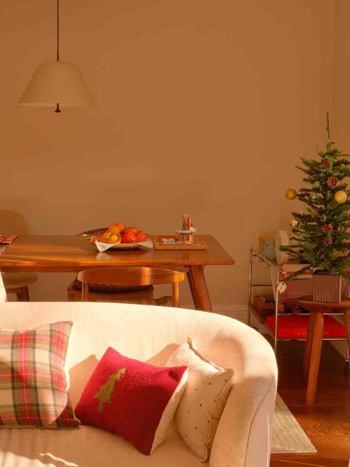 Warm beige-toned living and dining room featuring wooden dining table and cozy Christmas decor