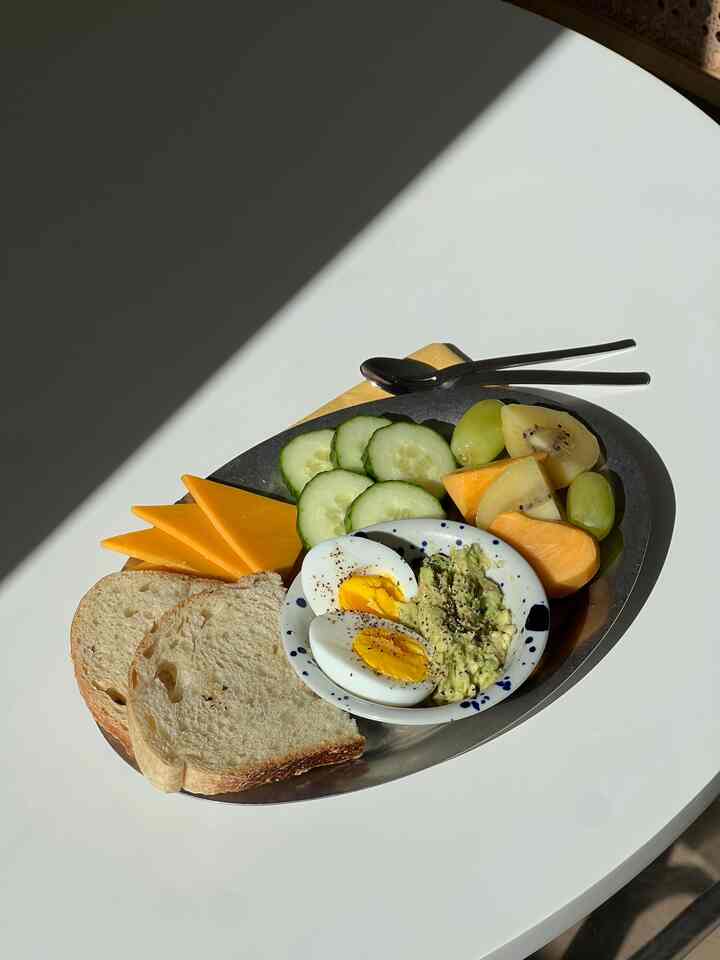 Bright white table in a minimal dining room setting featuring stainless steel plate with assorted breakfast items, creating a clean atmosphere