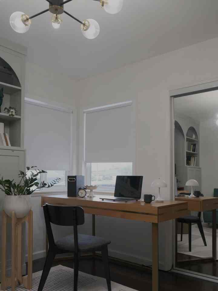 White walls with wood tone desk and black office chair in a calm, cozy home office space