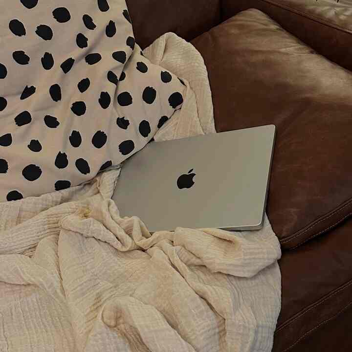 Brown leather sofa and beige blanket in living room, creating a comfortable and cozy atmosphere