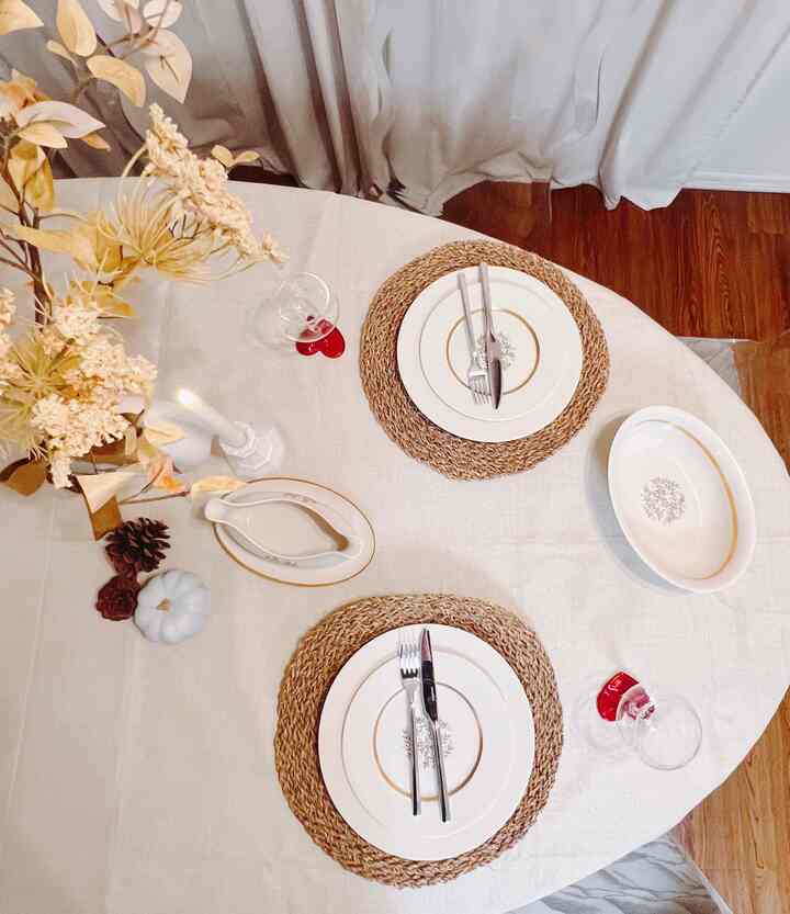 Natural toned dining room featuring two place settings, simple candles, and vase creating a cozy atmosphere