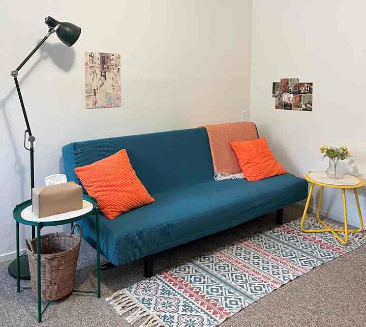 Simple living room with a blue sofa and orange cushions, creating a warm and cozy atmosphere