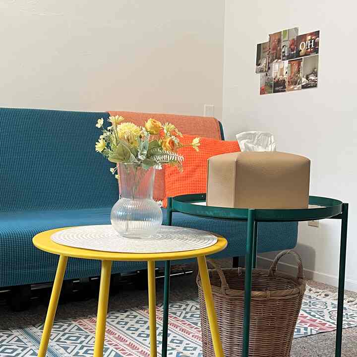 A compact living room and home office space featuring a yellow table and teal sofa, creating a bright and simple atmosphere.