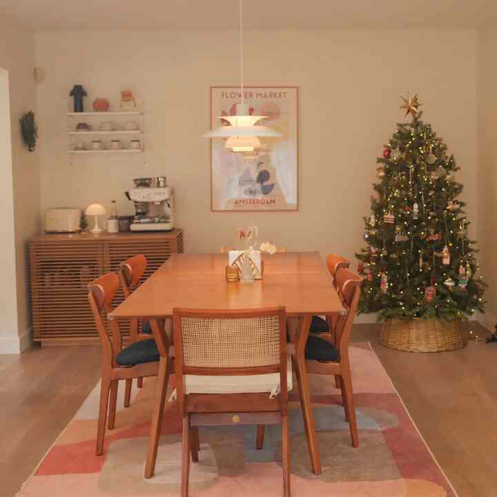 Warm dining room with white walls, brown wooden dining table, and Christmas tree decorated in red and white accents