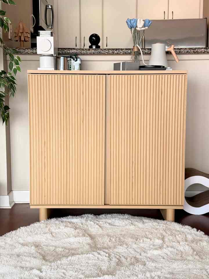 Warm wood-tone living corner featuring a wooden cabinet and fluffy white rug creating a cozy home cafe atmosphere