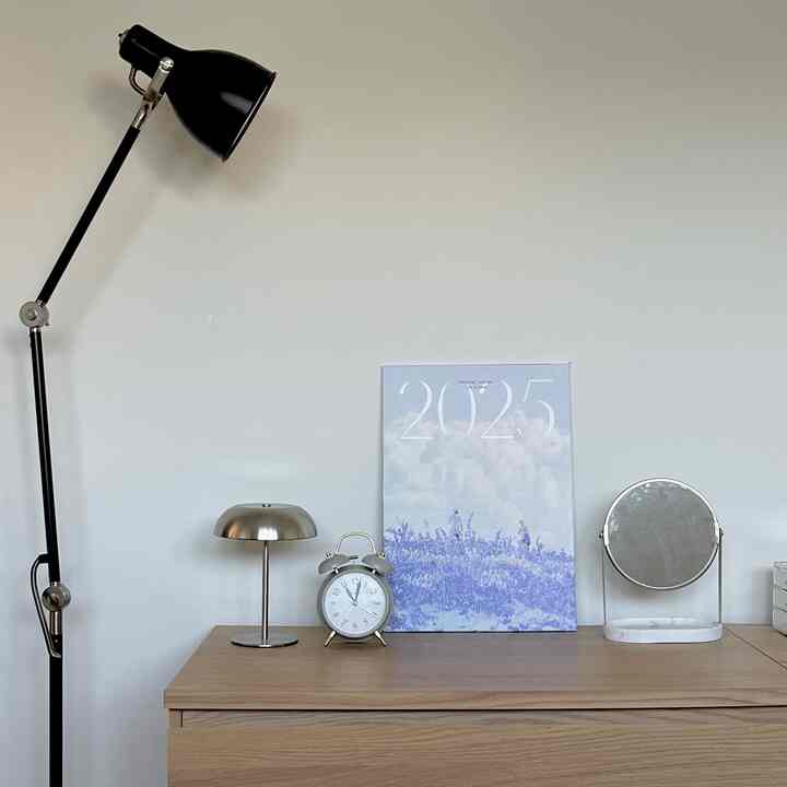 Clean bedroom space featuring natural wood dresser and modern black floor lamp with a simple, serene atmosphere