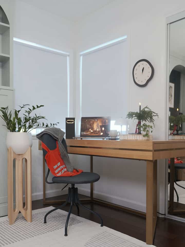 Modern home office with white walls and wood-tone desk, cozy corner featuring mood lighting and a wall clock