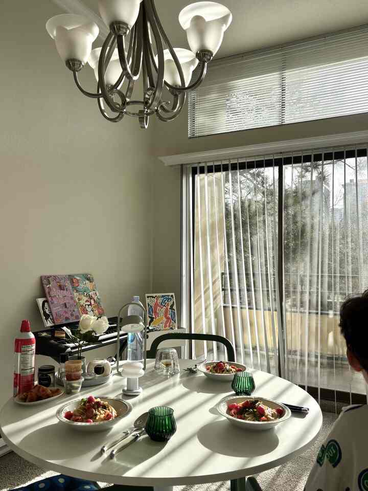 White-toned dining room featuring a round table with pasta dishes and tableware in a cozy atmosphere