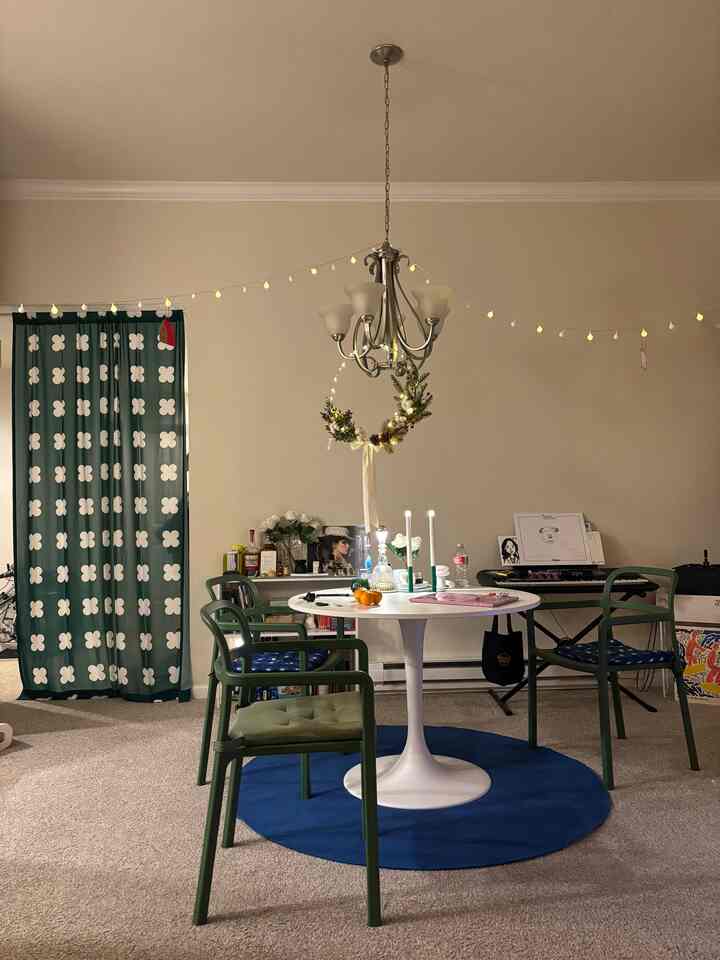 White and green toned living dining space featuring a round dining table, green chairs, Christmas garland, and candles for a cozy holiday atmosphere